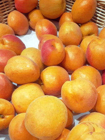 Close-up of organic apricots in bulk. Natural fruit background. Healthy eating. Wicker basket with freshly picked apricots for sale.の写真素材