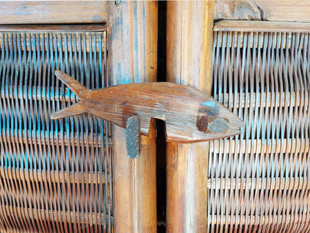 Detail of wooden fish in wicker woven texture. Close up natural bamboo mat as striped background. Oriental artificial rattan pattern.の写真素材