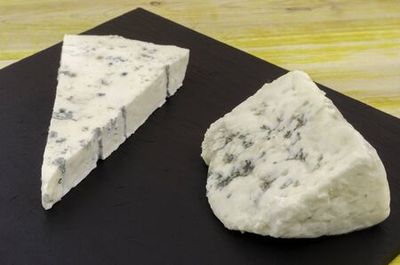 Roquefort and gornozola over slate plate and wood.の写真素材