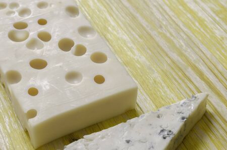 Gorgonzola and gruyere cheese over yellow wood.