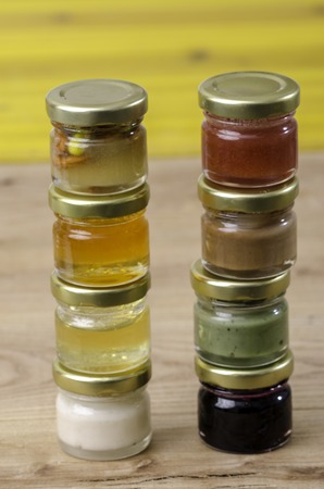Eight small jars of honey of differents flavors: mandarin, orange, strawberryの写真素材