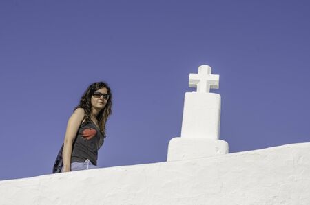 Girl with sunglasses and cross with blue background, Ibiza.の写真素材