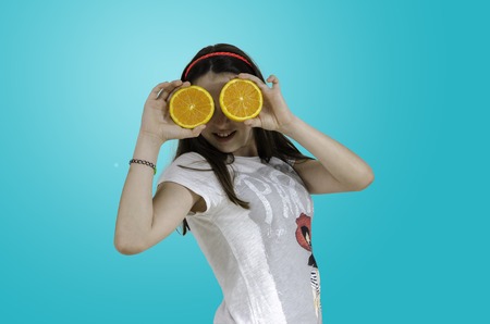 Girl playing with oranges over blue background, teenager.の写真素材