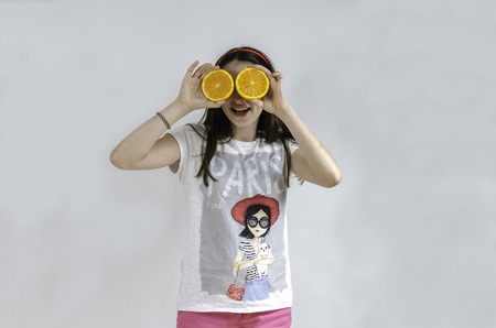 Girl with oranges in her eyes gray background, teenager.の写真素材