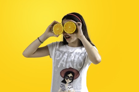 Girl with oranges in her eyes yellow background, teenager.の写真素材