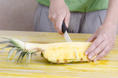Woman is cutting a pineapple over wood.の写真素材