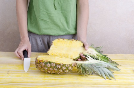 Woman is cutting a pineapple over wood.の写真素材