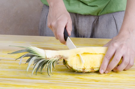 Woman is cutting a pineapple over wood.の写真素材