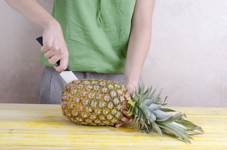 Woman is cutting a pineapple over wood.の写真素材