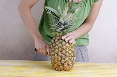 Woman is cutting a pineapple over wood.の写真素材
