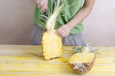Woman is cutting a pineapple over wood.の写真素材