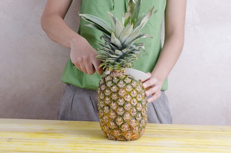 Woman is cutting a pineapple over wood.の写真素材