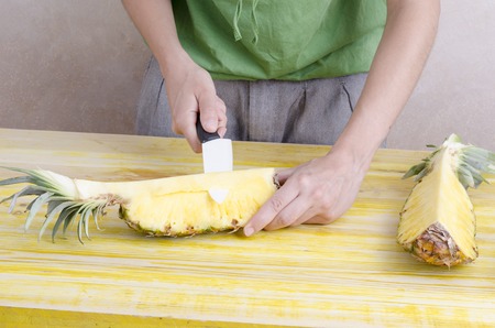 Woman is cutting a pineapple over wood.の写真素材