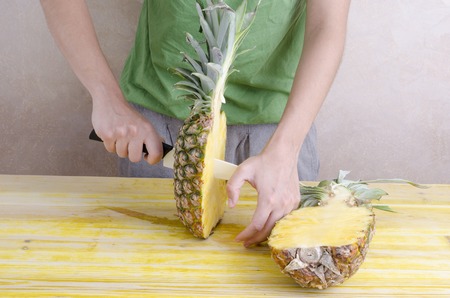 Woman is cutting a pineapple over wood.の写真素材