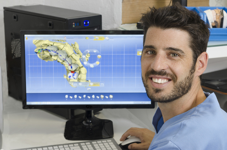 Handsome dentist is working with computer in the lab.の写真素材
