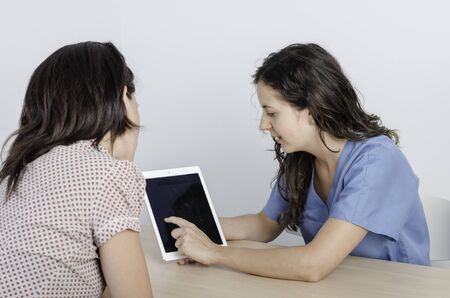 Young doctor/ physiotherapist with her consultation with a woman patient.の写真素材
