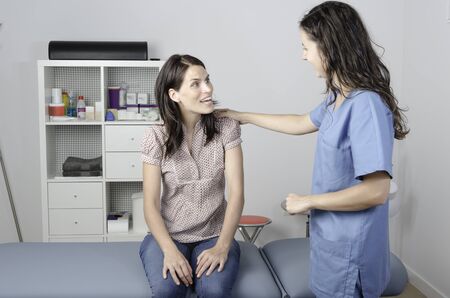Young doctor/ physiotherapist with her consultation with a woman patient.の写真素材