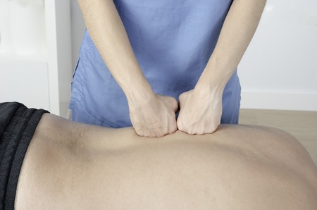Physiotherapist doing a massage technic on men back.