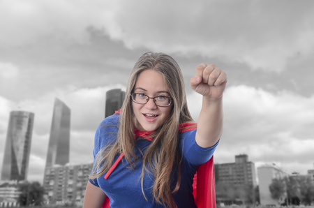 Woman superhero with red cape, city background.の写真素材