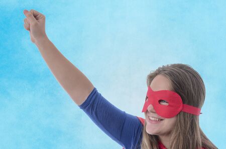 Woman superhero with red cape, blue background.の写真素材