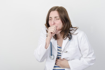 Female doctor sneezing, she is ill.の写真素材