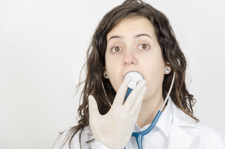 Young woman doctor with stethoscope in her mouth.の写真素材