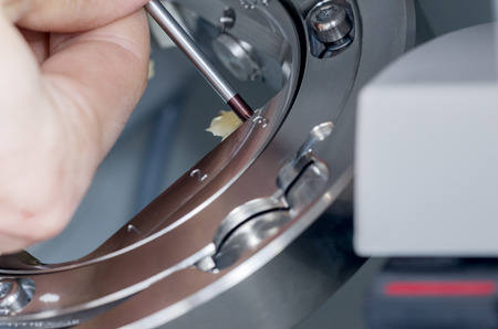 Closeup of dental technician unscrew the hybrid ceramics the milling machine.の写真素材