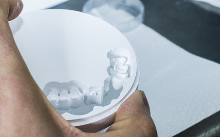 Closeup  of dental technician is extracting teeth in the zirconia disc.の写真素材