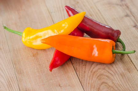 orange, yellow and red bell pepper on wood background
