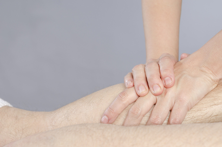 Closeup of hands of chiropractor/physiotherapist doing calf muscle massage to man patient.の写真素材