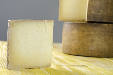Whole wheel of sheep milk cheese over yellow wood.の写真素材