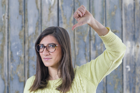 Young hipster woman with glasses and thumb down, retro style color tones