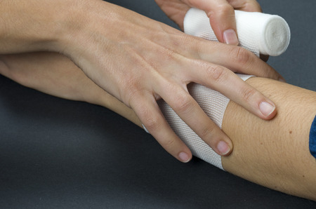 Close-up of woman doctor bandaging a hand.