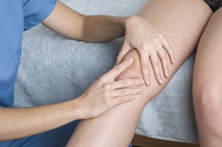 Physiotherapist, chiropractor doing a patellar mobilization, Knee pain.