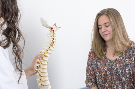 Doctor showing a skeleton to a patient. Back pain.の写真素材