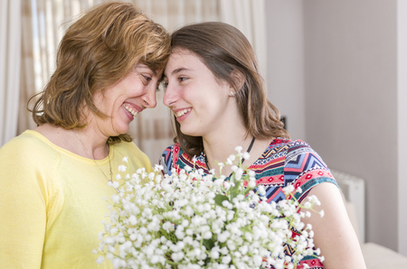 Woman and child with a bouquet of flowers in their house. Mother's day.の写真素材