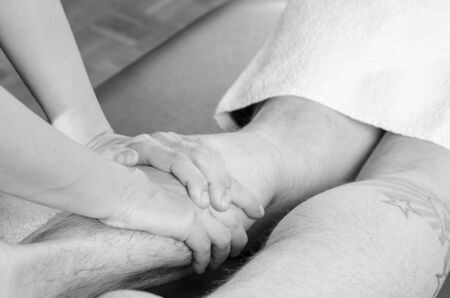 Closeup of hands of chiropractor/physiotherapist doing calf muscle massage to man patient.の写真素材