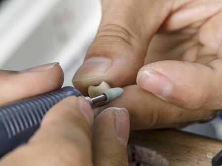 Dental technician modelling an implant ceramic tooth with a drillの写真素材