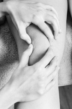 Physiotherapist, chiropractor doing a patellar mobilization, Knee pain in silhouetteの写真素材