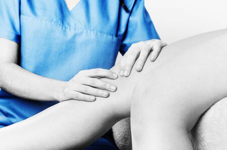 Physiotherapist, chiropractor doing a patellar mobilization, Knee pain in silhouette, color and black and white.の写真素材