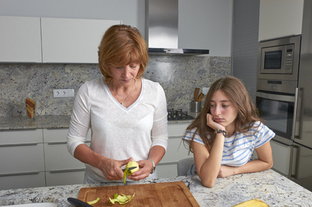 Teenage daughter is boring looking at her mother cooking. の写真素材