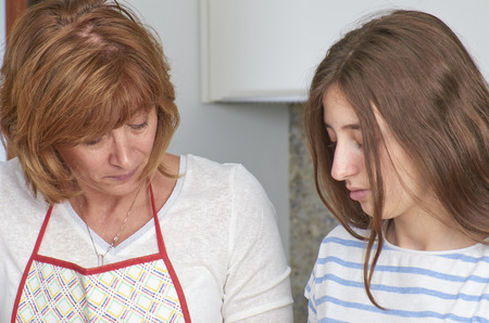 Mother and her teenage daughter are cooking together in the kitchen, prepare a salad. Vegan Family. の写真素材