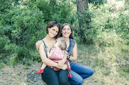 Adorable lesbian couple with their baby girl in nature.の写真素材