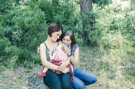 Adorable lesbian couple with their baby girl in nature.の写真素材