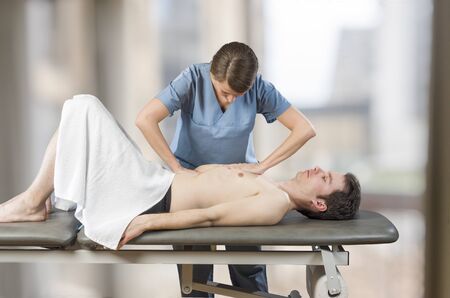 Physiotherapist, chiropractor is doing an activation of the diaphragm. Massage to a man patient....