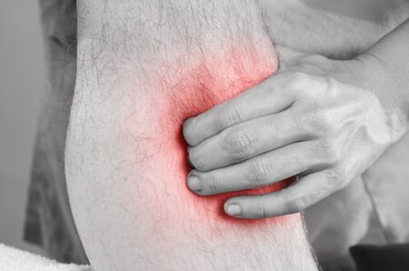 Closeup of hands of chiropractor, physiotherapist doing calf muscle massage to man patient....