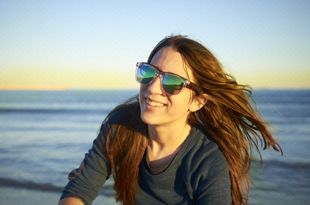 Portrait of young woman with sunglasses at sunset.