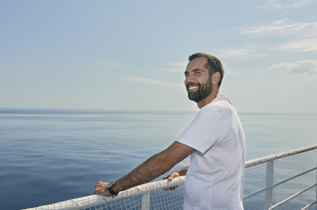Handsome man smiling on the deck of a ship during holidaysの写真素材