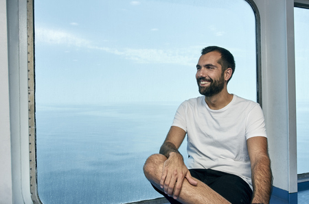 Handsome man smiling on the deck of a ship during holidaysの写真素材