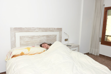 Woman placidly sleeping in bed in her large bedroomの写真素材